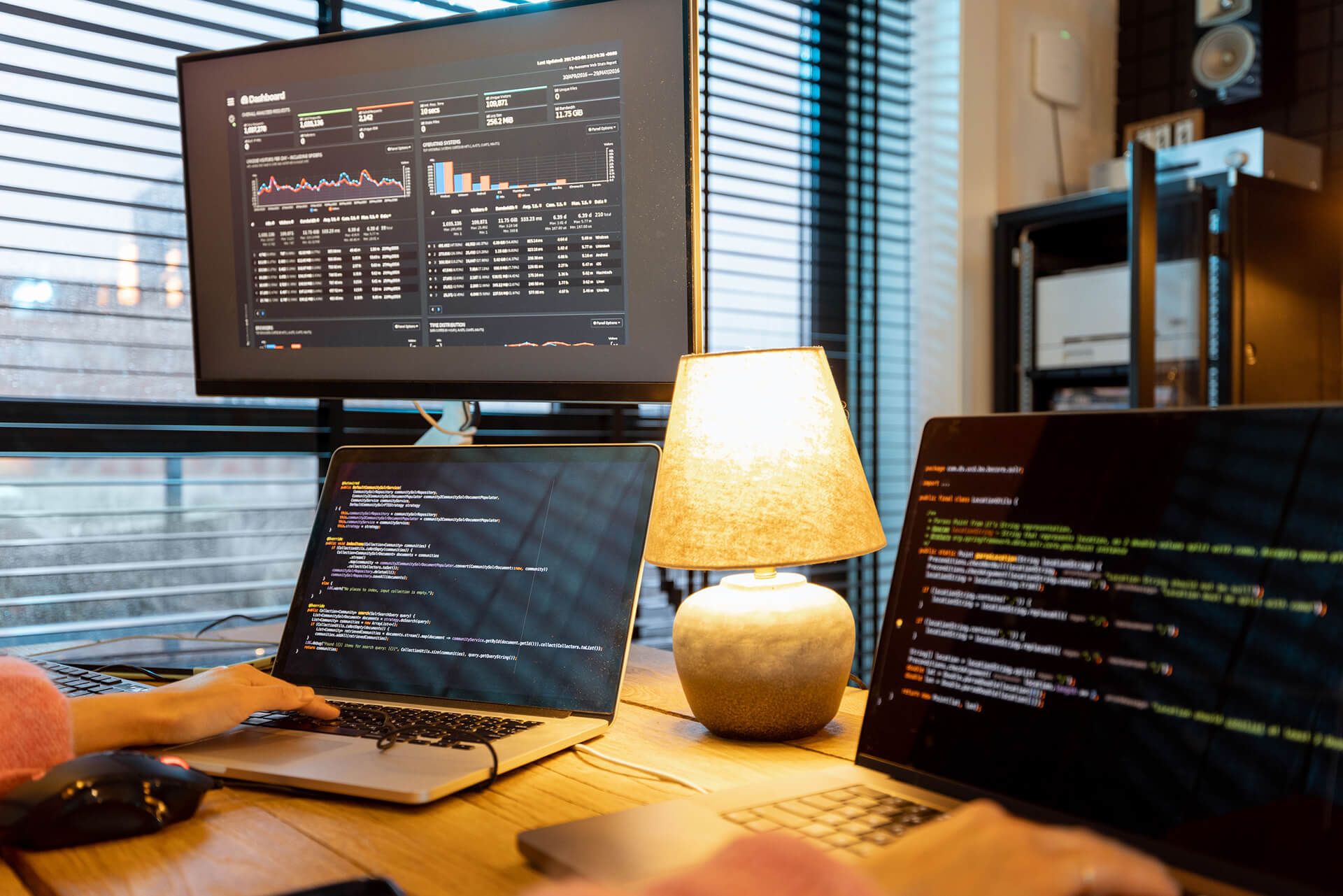 Postazione di lavoro con un monitor che mostra una dashboard di dati e un portatile con il codice di un’analisi